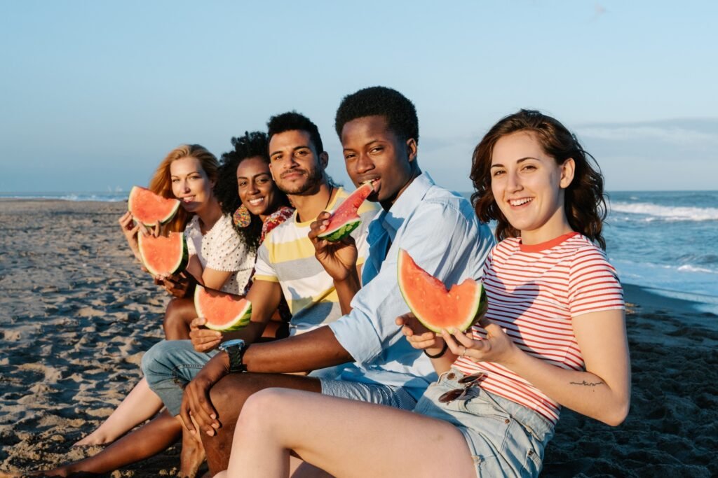 Friends eating water melon on a beach Photo by Kaba Camara