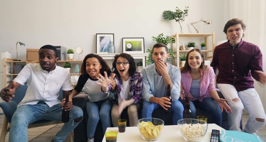 Group of young people sitting on couch and watching tv