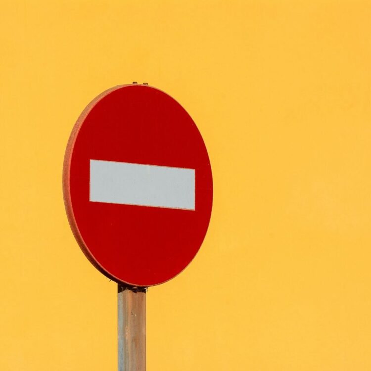 A red and white no entry sign against a yellow background
