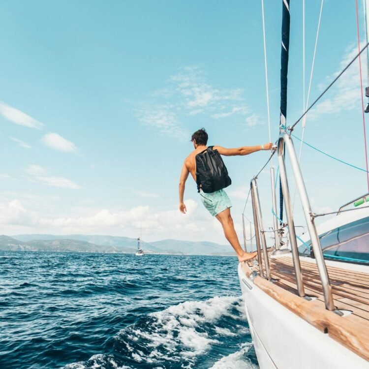 Man Wearing Backpack Standing On Side Of Boat During Daytime