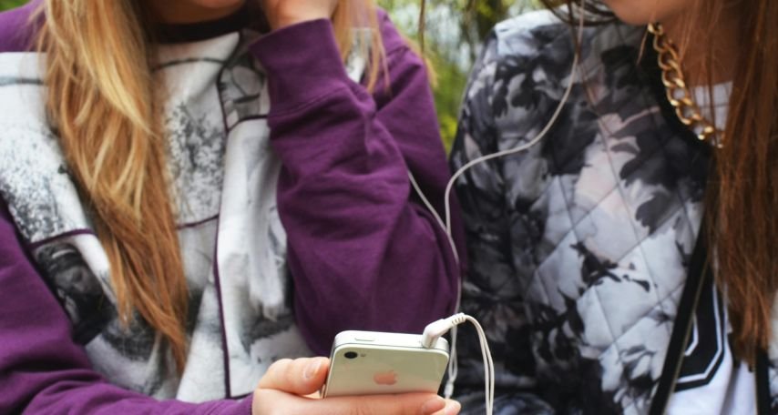 Two Women Listening on White Iphone 4 Using Earbuds