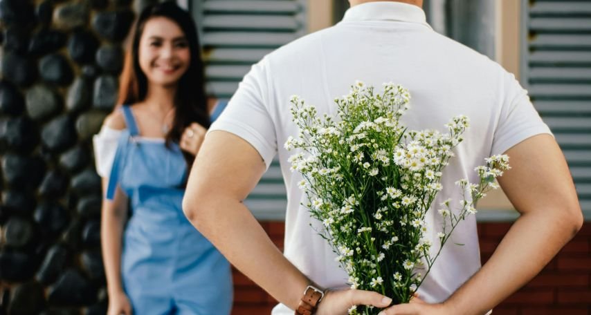 Man Holding Baby's-breath Flower in Front of Woman Standing Near Marble Wall
