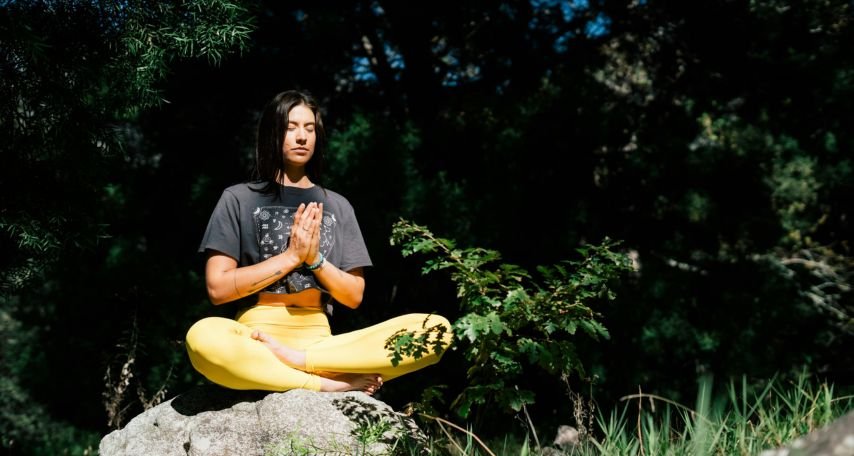 Photo of Woman Doing Yoga While Sitting on Rock