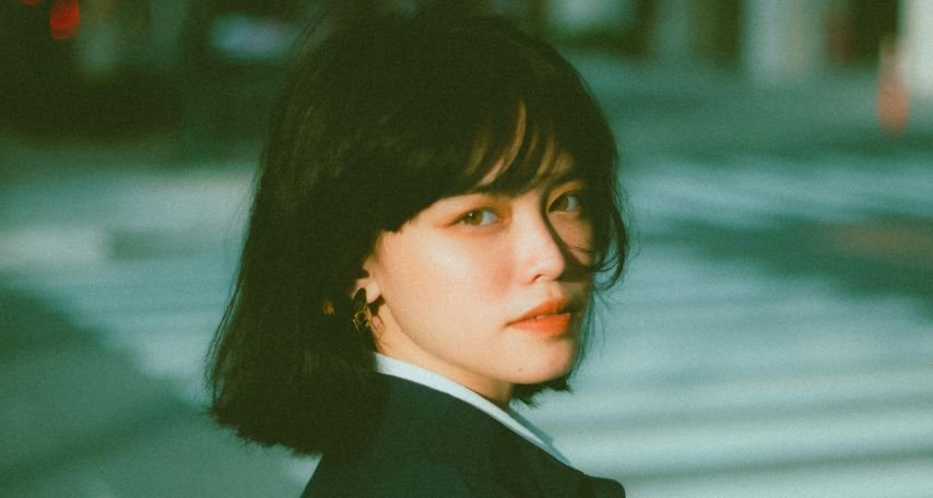 Pensive young ethnic businesswoman looking at camera on street
