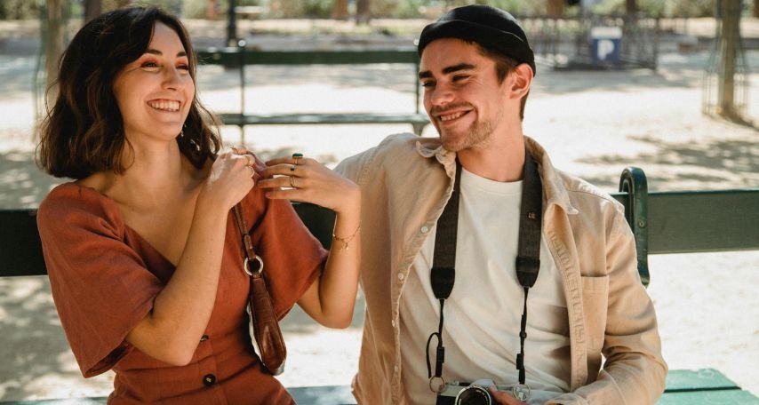 Woman and man smiling sitting on a bench