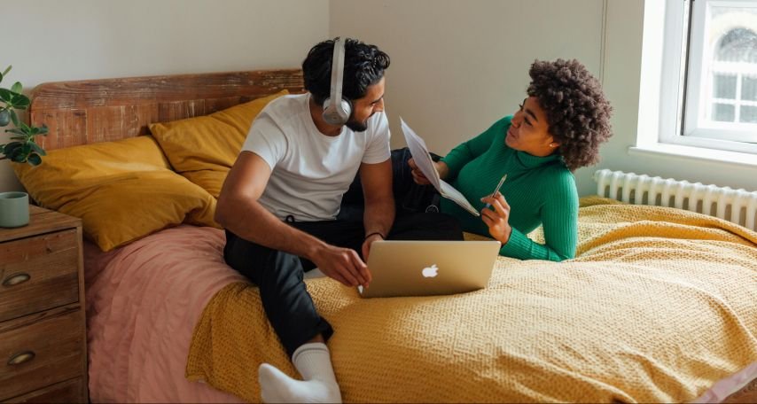 A Man and Woman Having Conversation while Working on the Bed