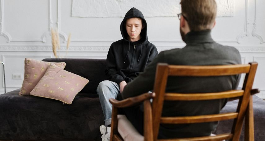 Man in Turtle Neck Sitting Beside Boy in Black Hoodie