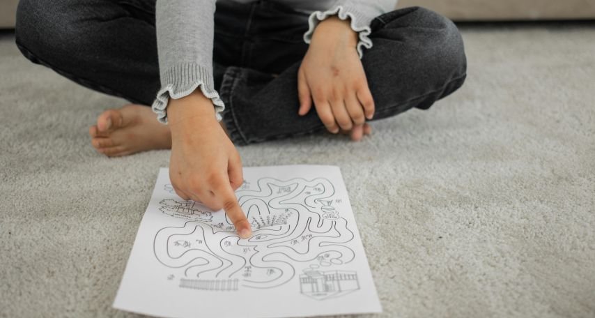 Kid sitting on rug and passing painted labyrinth