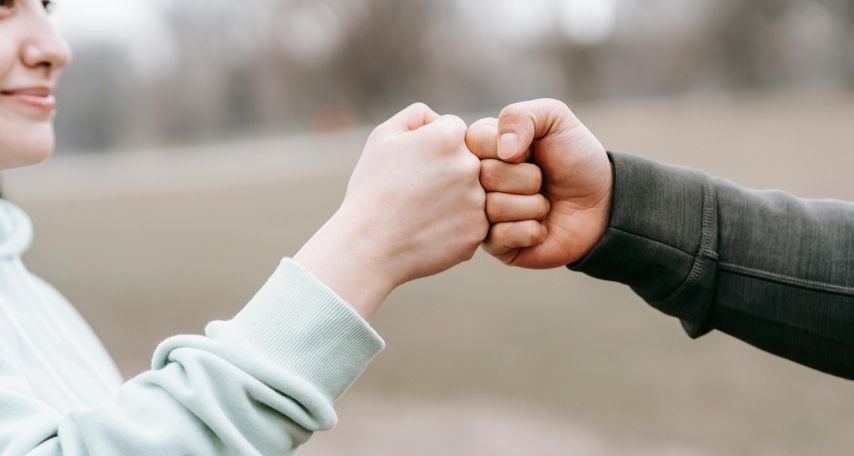 Man and happy woman greeting each other with fist bump