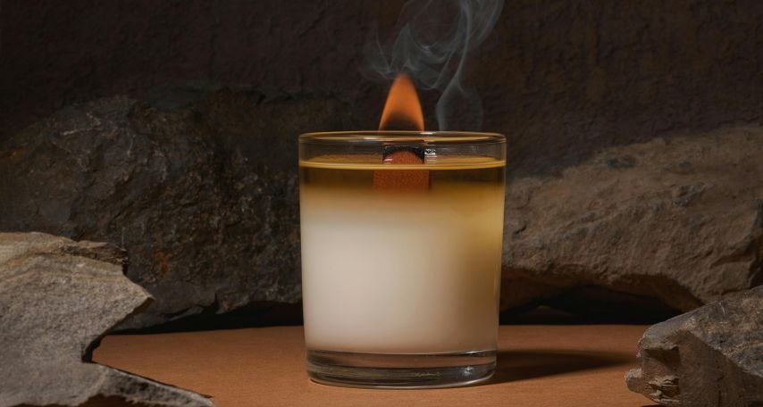 Burning fuming candle placed near boulders
