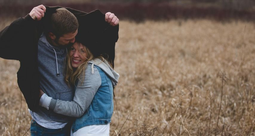 Man and Woman Hugging on Brown Field
