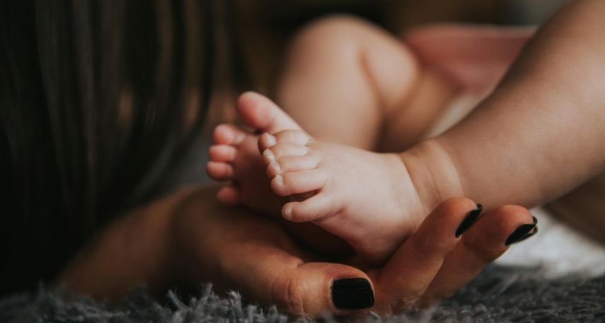 Person Holding Baby's Feet in Selective Focus Photography
