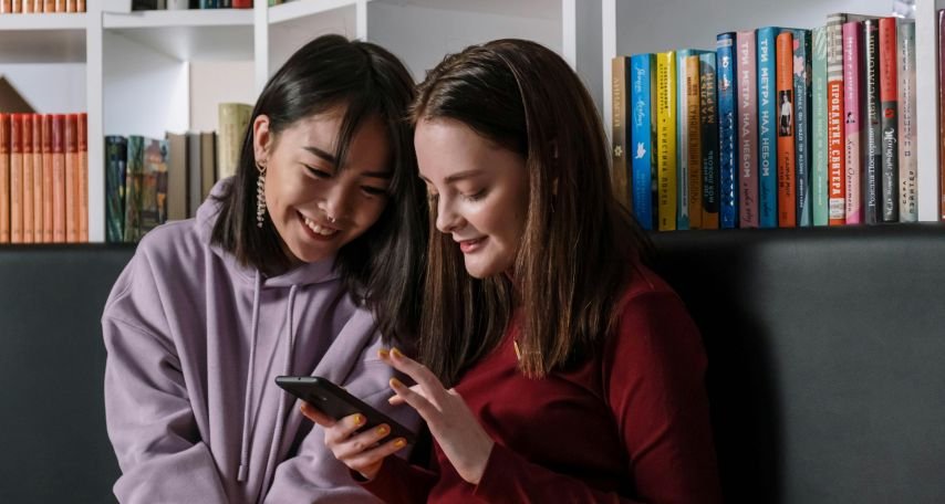 A Girl in Red Sweater Holding Her Phone while Talking to Her Friend