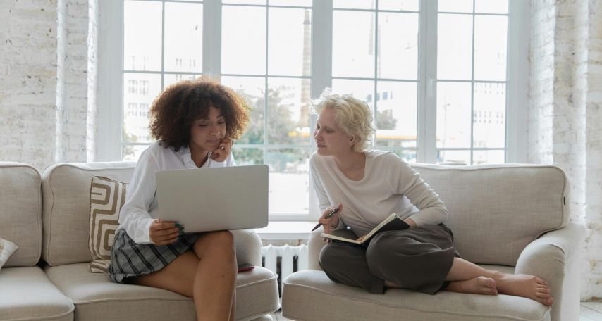 Young women working on project together using a laptop in apartment