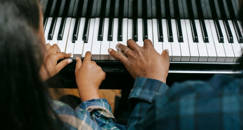Teacher playing piano with student