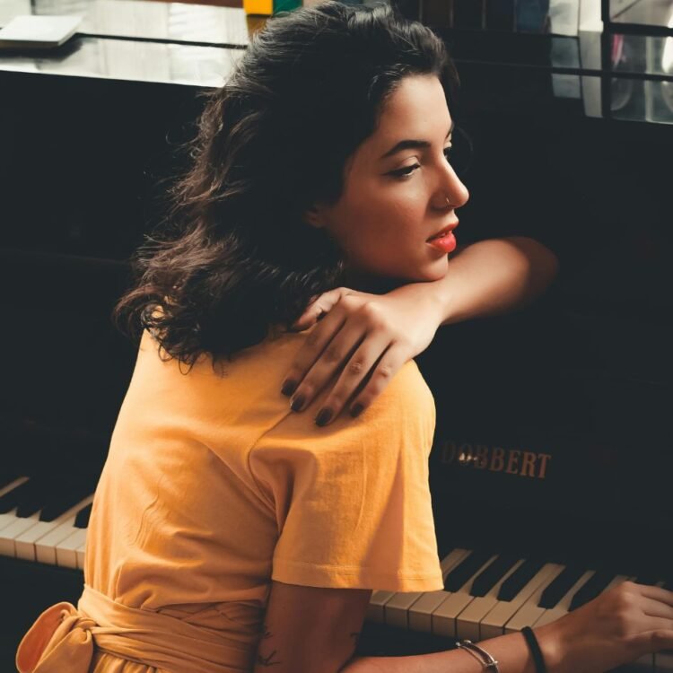 Woman In Yellow Dress Sitting In Front Of Black Piano