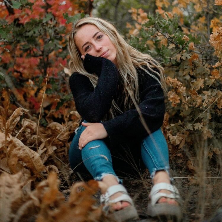 Blond Woman Sitting on Ground in Autumn
