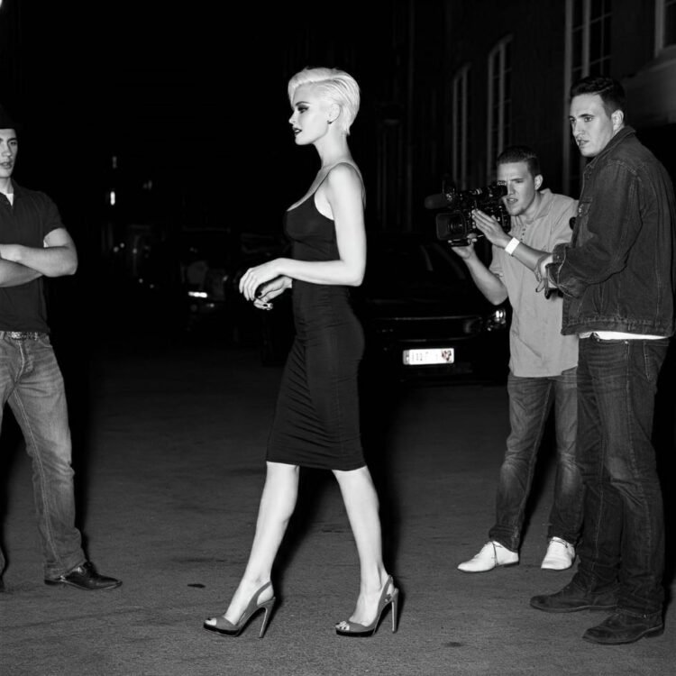 Blonde woman in black dress walks past two guys, captivating them