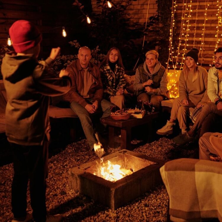 Family playing charades at bonfire in garden
