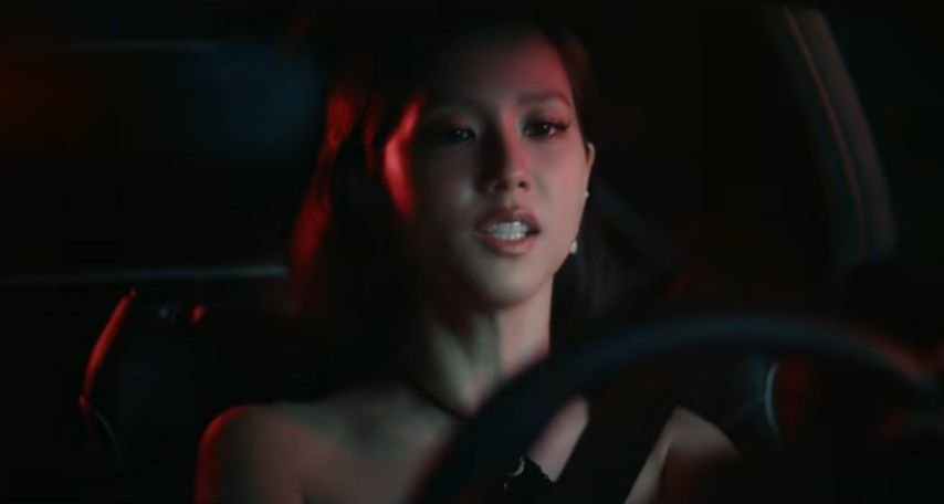Jisoo driving through a dark tunnel with red lighting