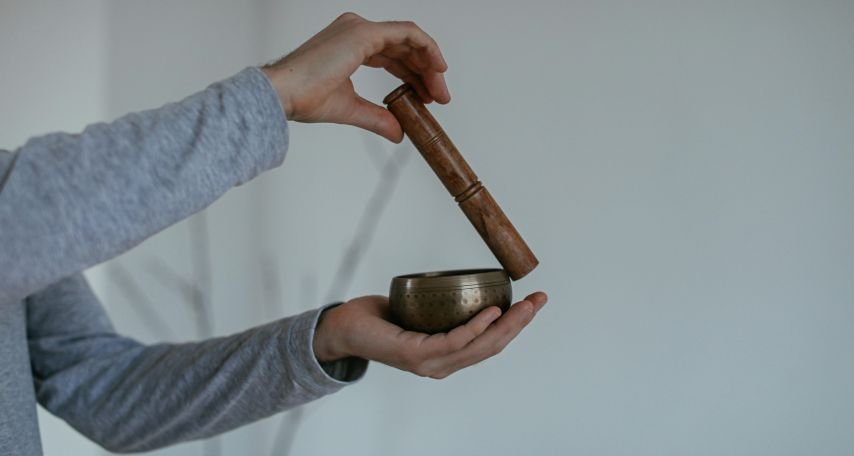 Person Holding a Wooden Mallet and Singing Bowl