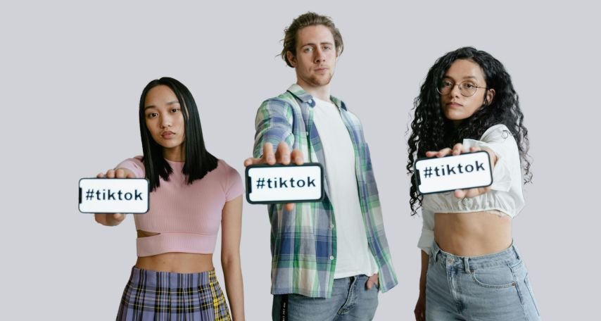 Three young individuals holding smartphones displaying the hashtag #tiktok