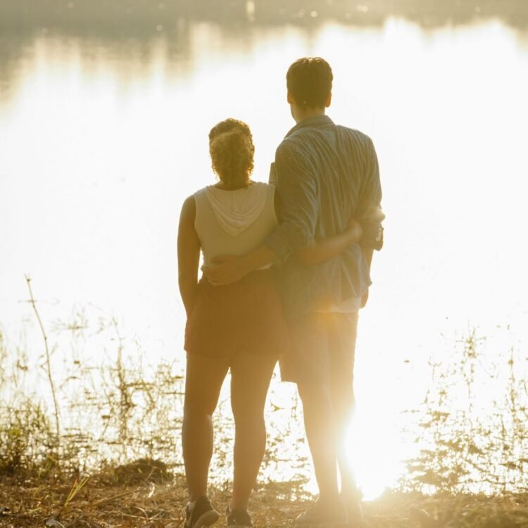 Couple hugging and enjoying lake view at sundown