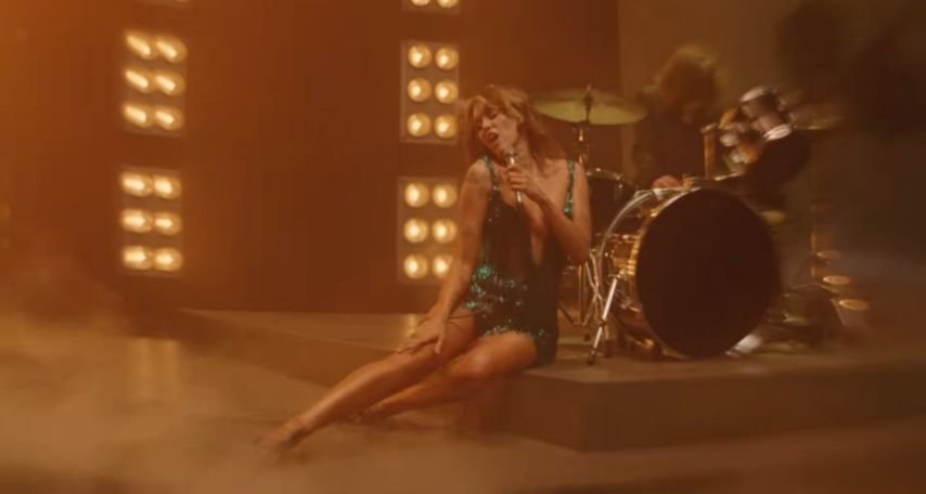 Miley Cyrus lies on stage in a green dress during dreamy End of the World video.